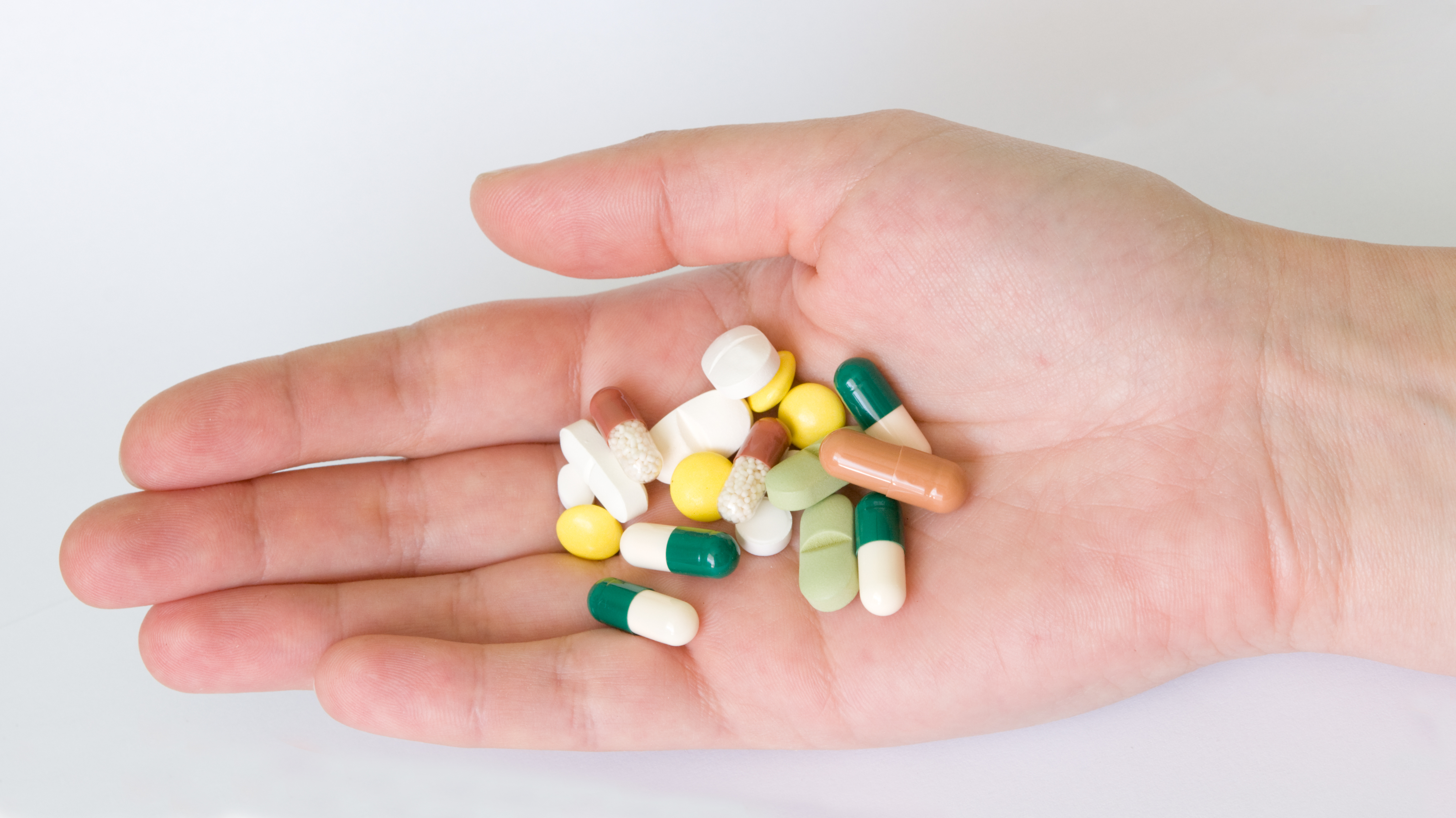 Hand with different forms and colours pills and capsules